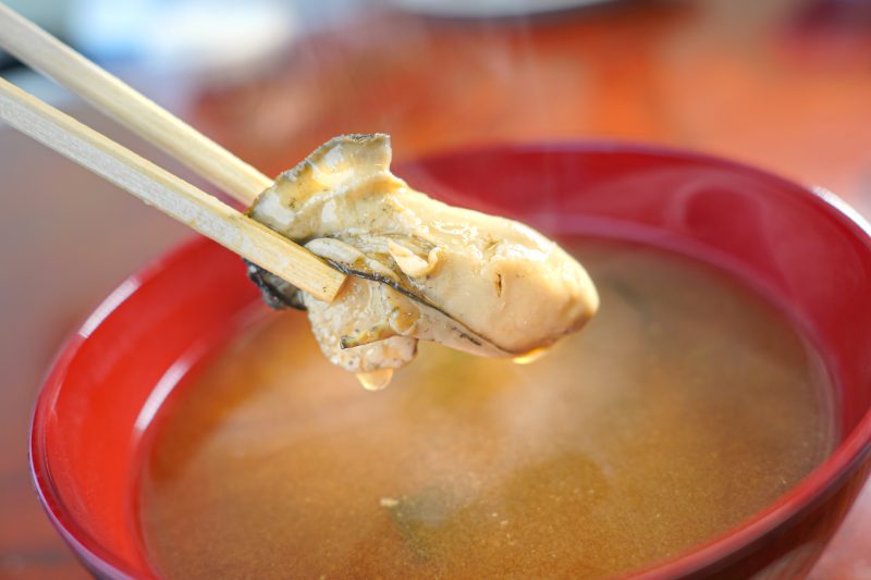 牡蠣の味噌汁から牡蠣の身を箸でつかむ